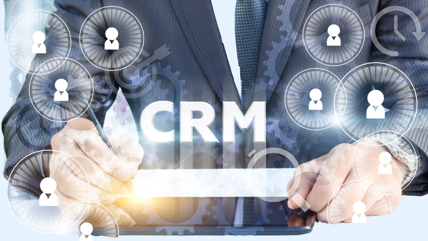 Hands using a tablet to manage CRM, with floating circular user/profile icons around gear graphics