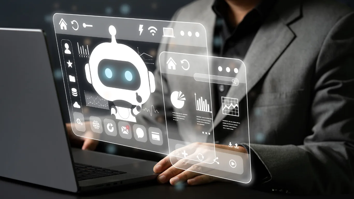 Person at a laptop with a floating holographic dashboard showing a robot avatar, charts, and icons (tech/concept image).