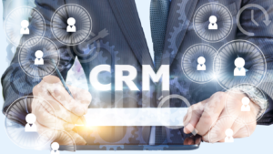 Hands using a tablet to manage CRM, with floating circular user/profile icons around gear graphics
